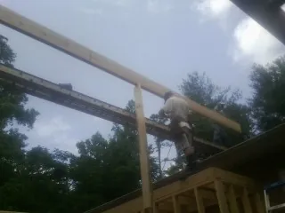Carpenter setting a ridge beam over a new addition frame — Ice Dam Removal by Roofing Brothers in Decker