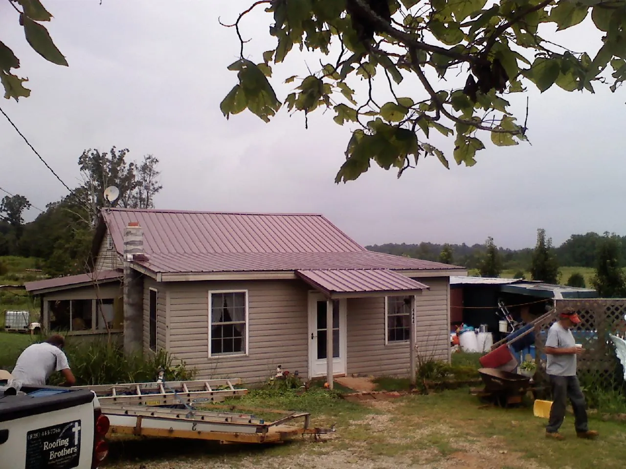 Crew finishing a mauve metal roof on a small farmhouse in Decker