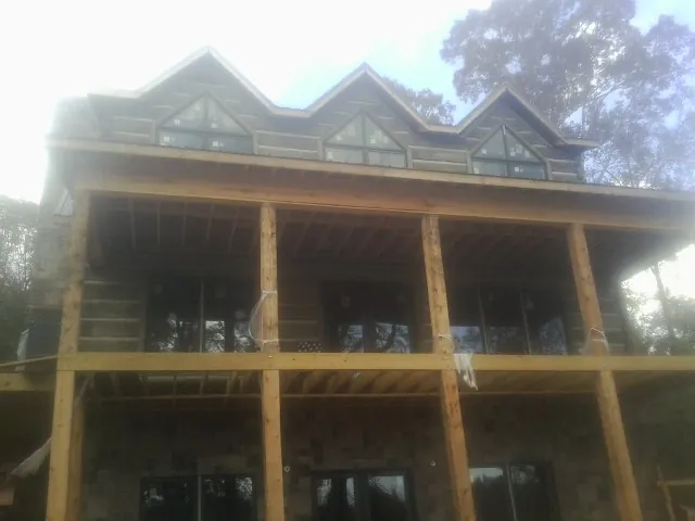 Dormers and porch framing on a large log home under construction — Roof Coating work by our crew in Decker