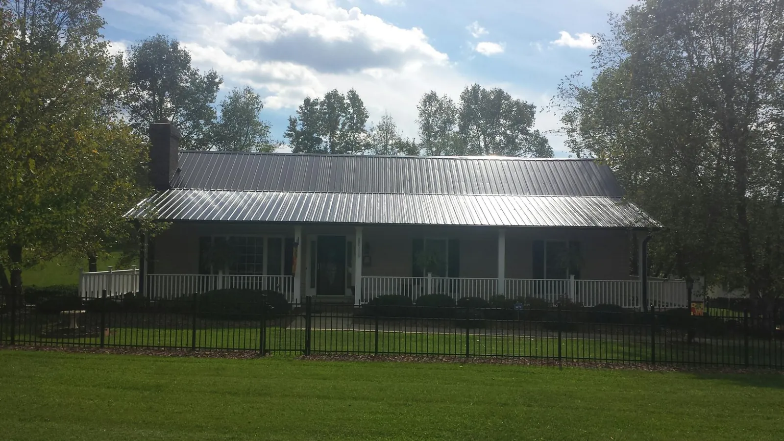 Gray metal roof on a brick ranch with a full width front porch — Gutter Guard Installation work by our crew in Decker